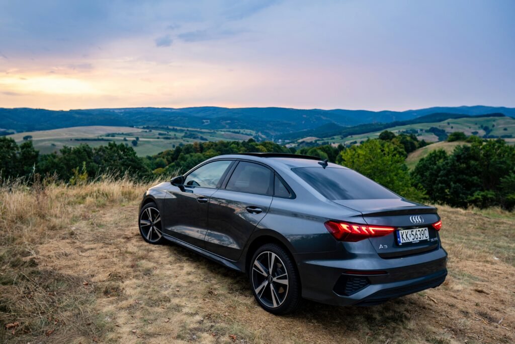 A sleek Audi A3 sedan parked on a hillside during a scenic sunset in Slovakia's countryside.