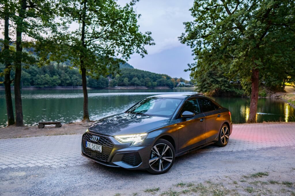 Audi sedan parked by a picturesque lake in Slovakia surrounded by lush greenery and serene water.